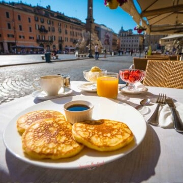 A plate of pancakes with a cup of orange juice in an italian cafe for breakfast.