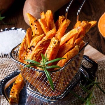 Sweet potato fries in a basket on a wooden table. featured image for sides for hamburgers.