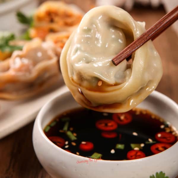 A bowl of dumplings with sauce and chopsticks.showcasing what sides to serve with dumplings