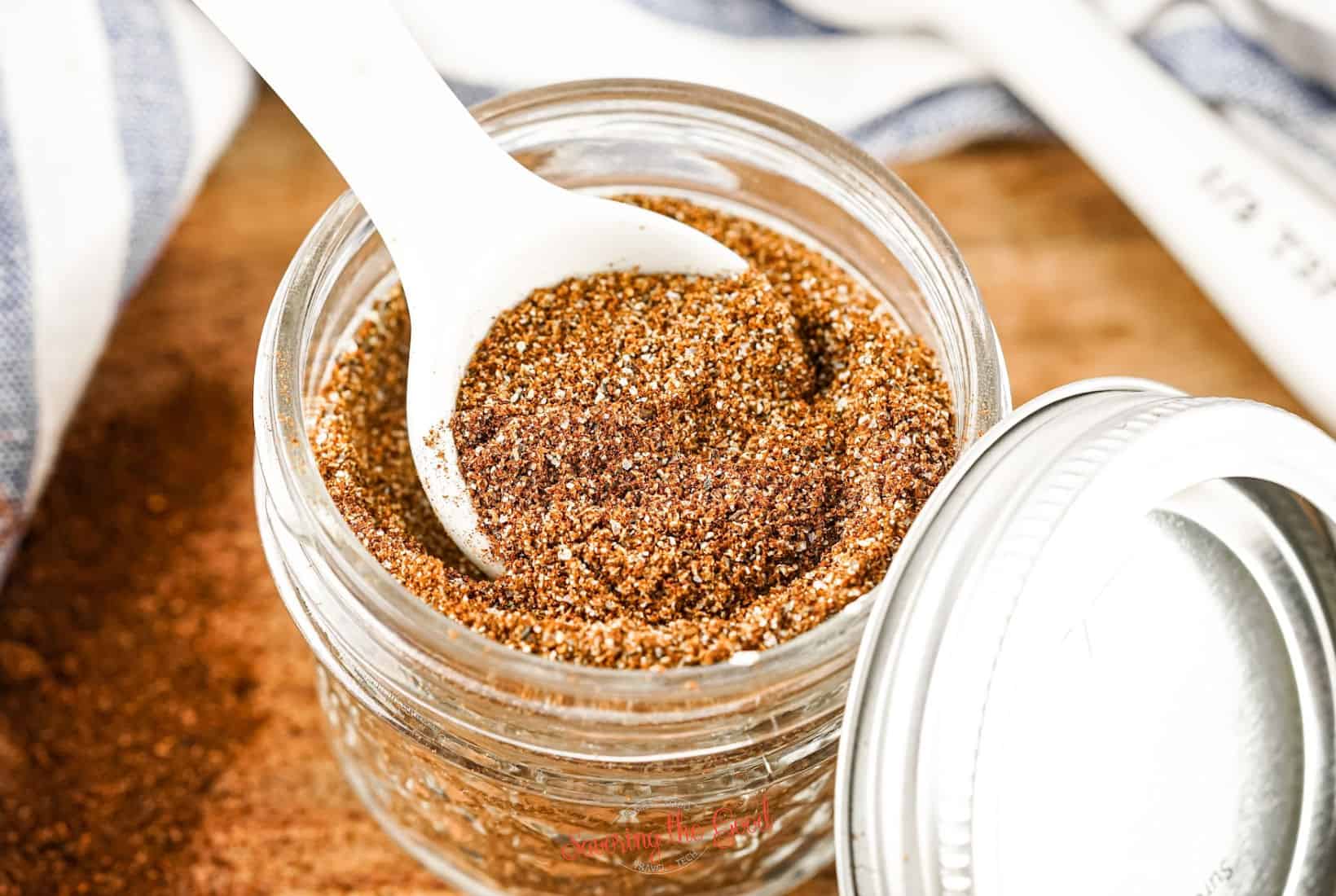 Homemade Chili Seasoning Recipe in a glass jar with a white spoon.
