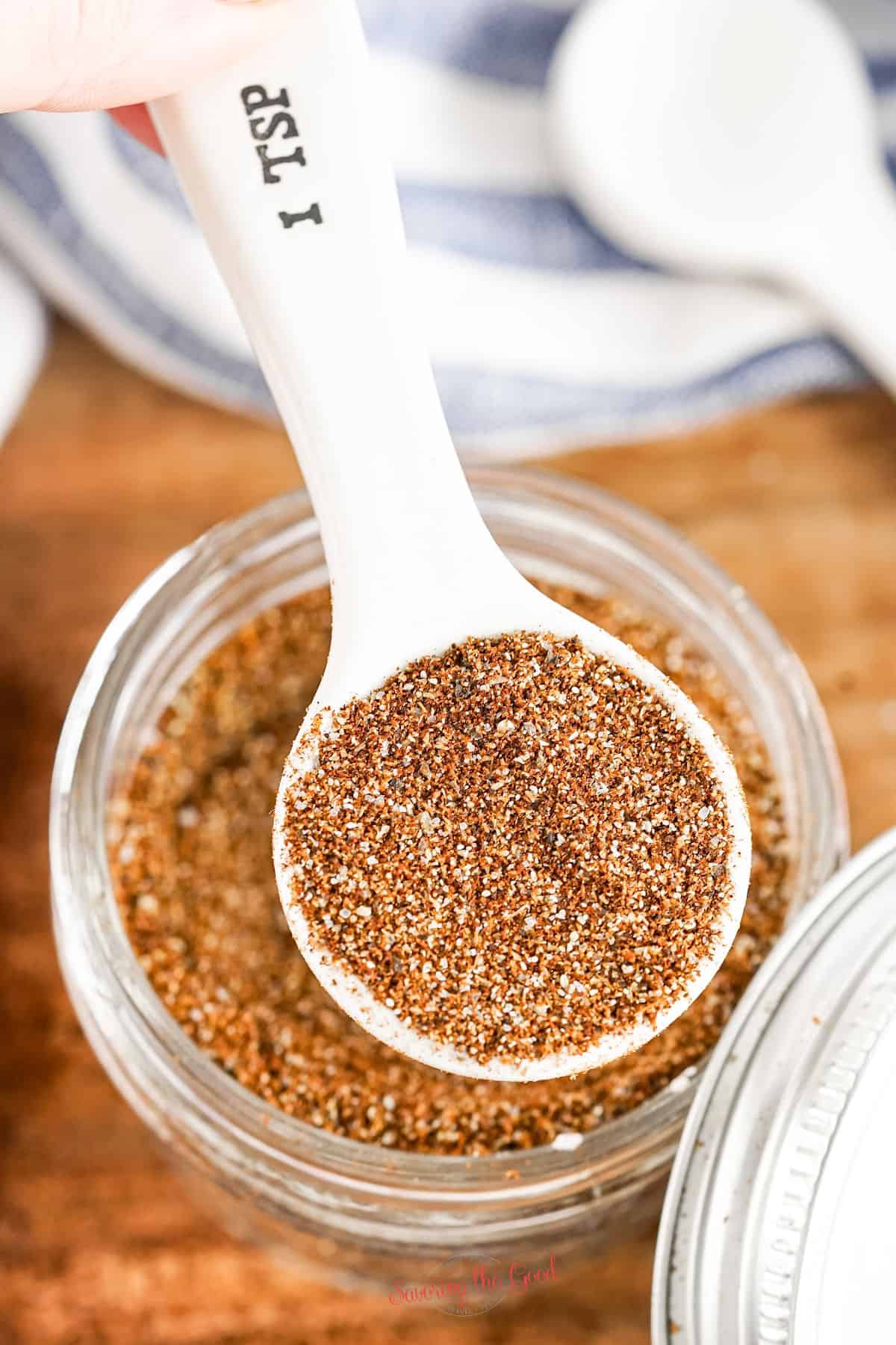 Homemade Chili spice mix seasoning in a glass jar and white spoon.