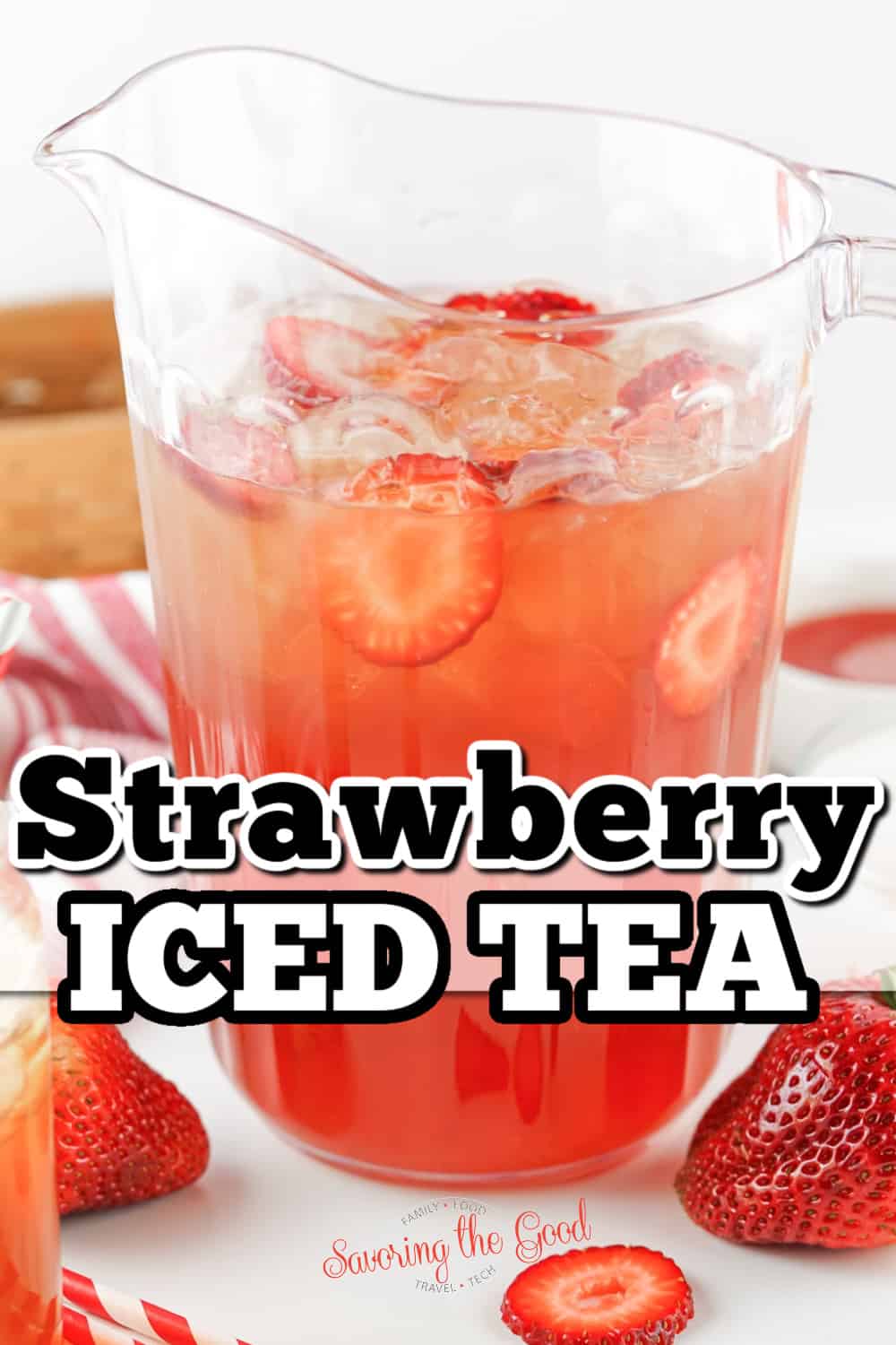 Strawberry iced tea in a pitcher with strawberries.