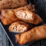 one buffalo chicken dip egg roll sliced open, showing texture inside stacked on top of other egg rolls