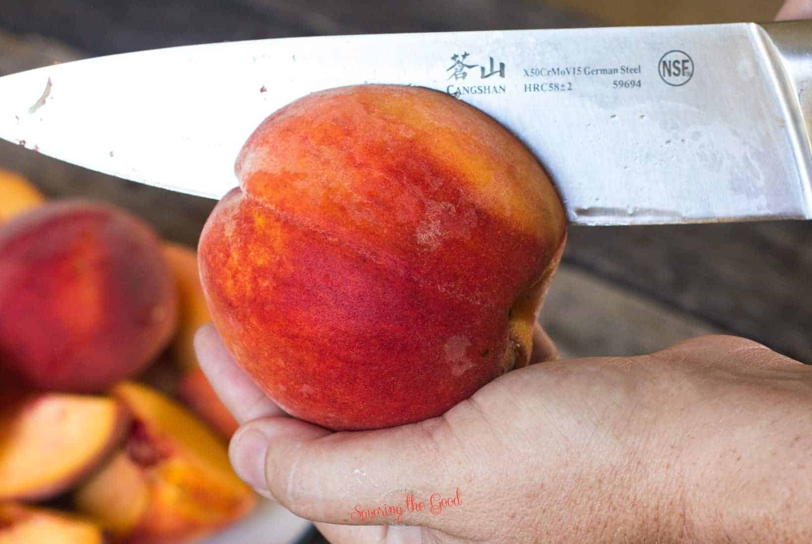 chef knife showing the propper technique for pitting a peach, slicing from end to end to free the flesh from the pit