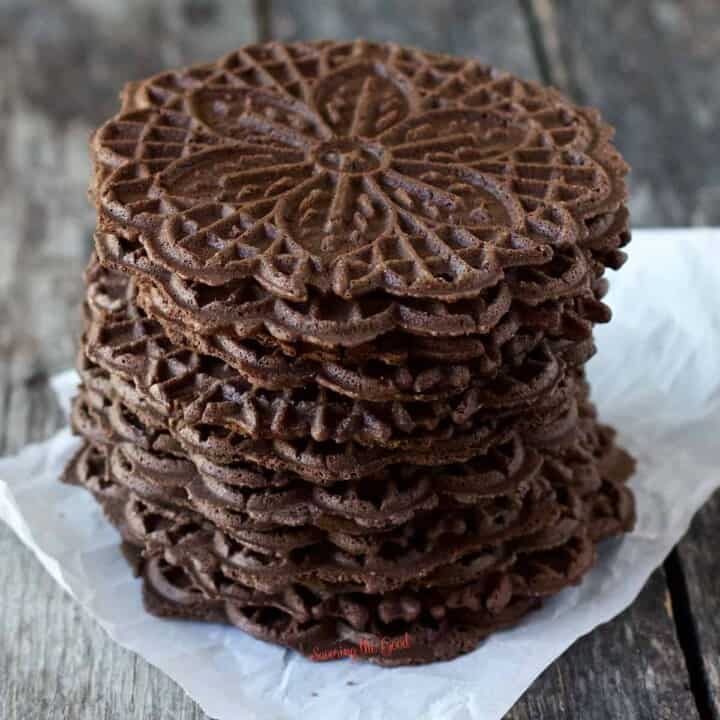 chocolate pizzelles stacked 7 high on a piece of white parchment paper