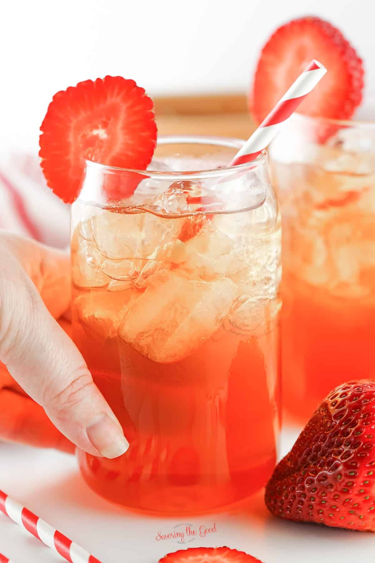 hand holding a glass of strawberry iced tea recipe.