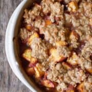 square image of peach crumble in a white stoneware dish