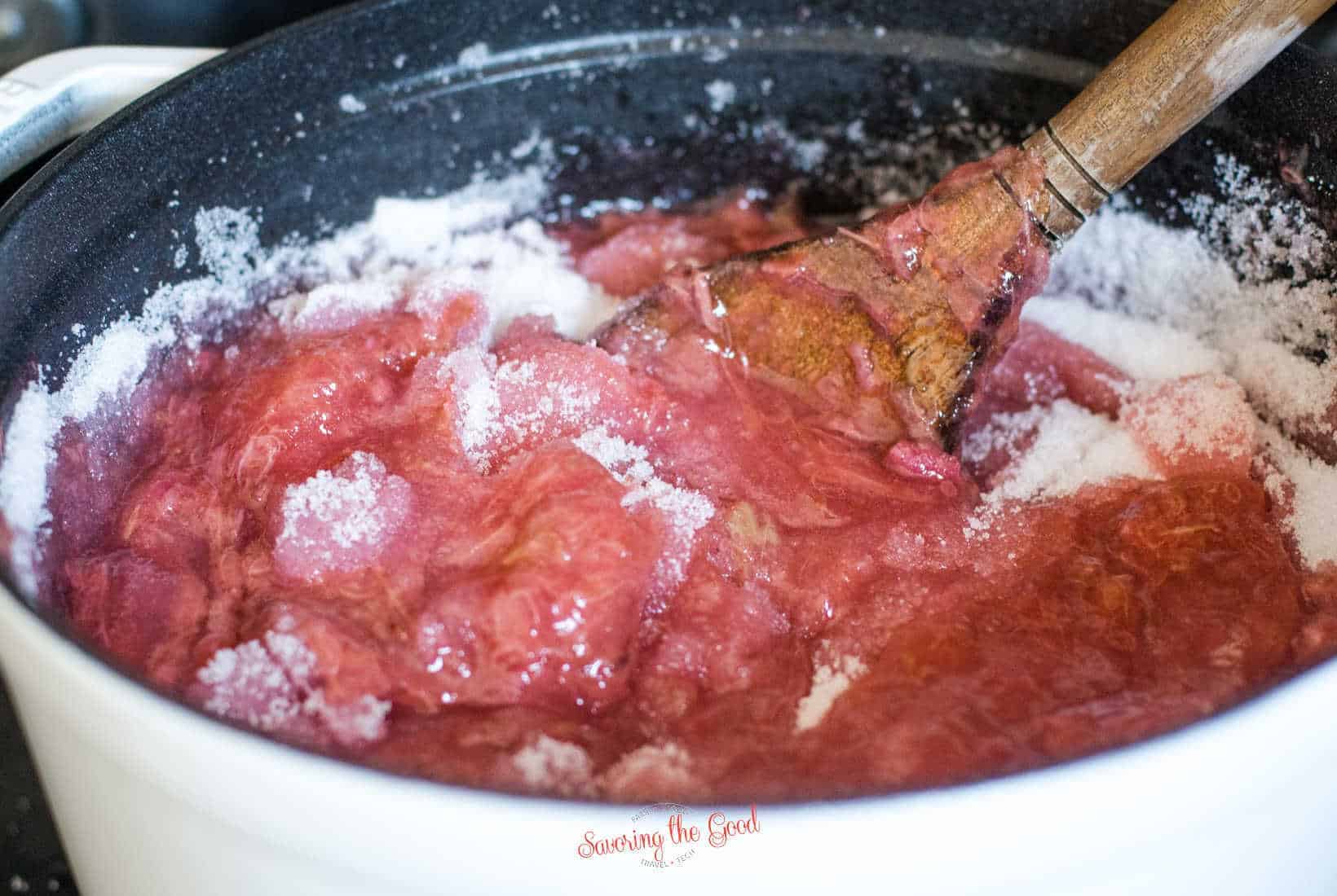 stirring the sugar into the cooked Rhubarb for jam