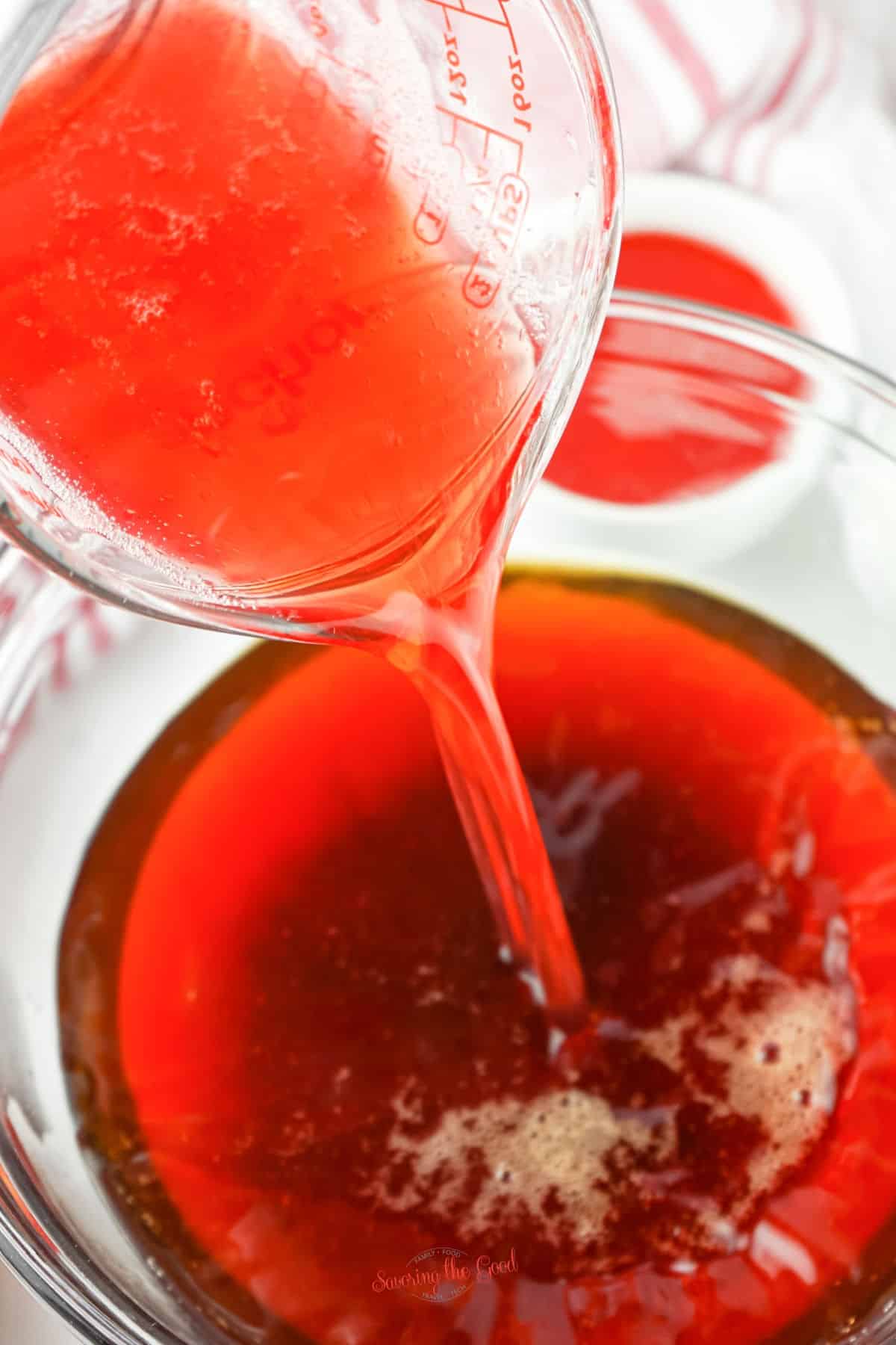 strawberry iced tea being poured into a clear glass bowl.