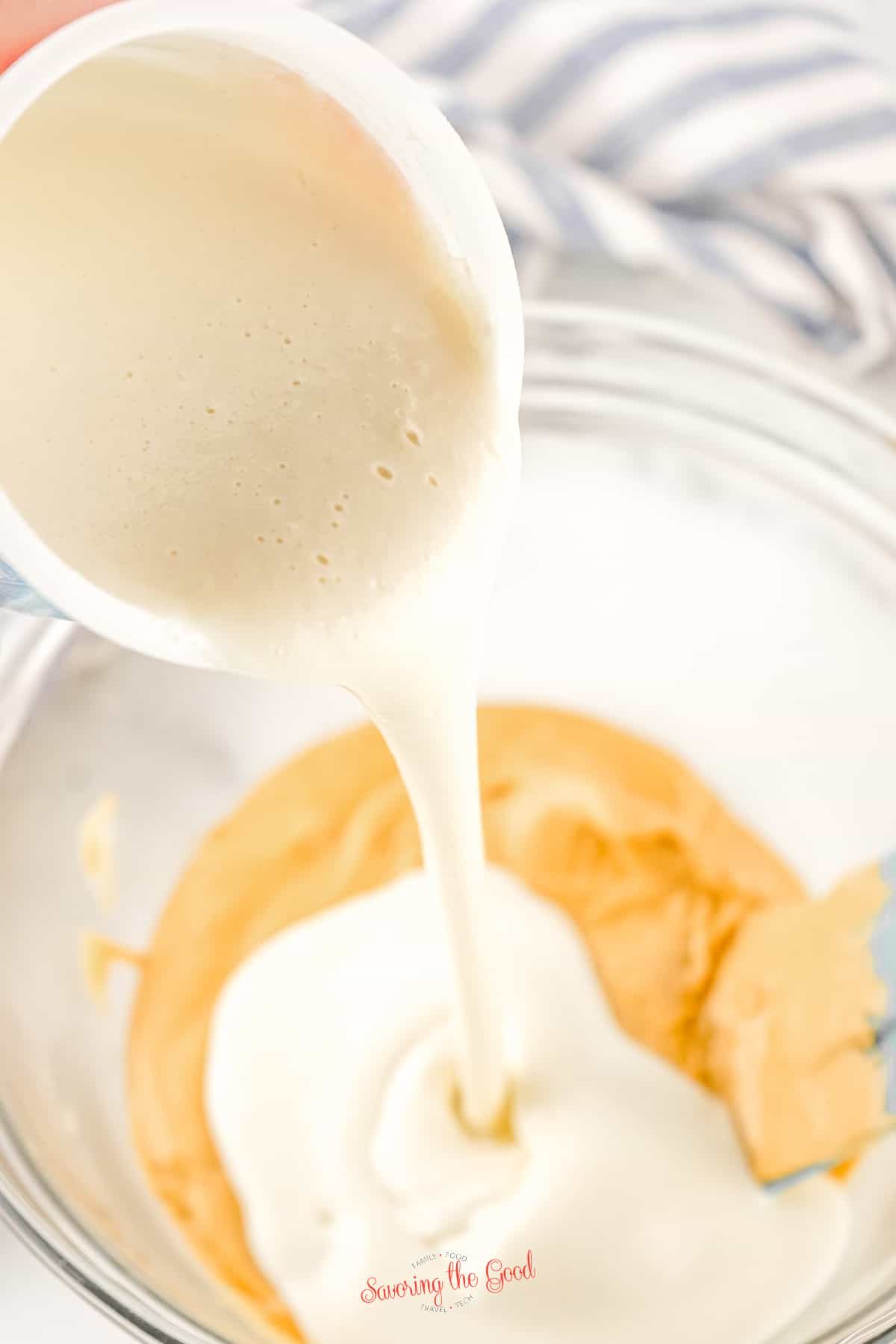 A bowl of melted icing peanut is being poured into a bowl of peanut butter chips, melted, 2 ingredient peanut butter fudge recipe.