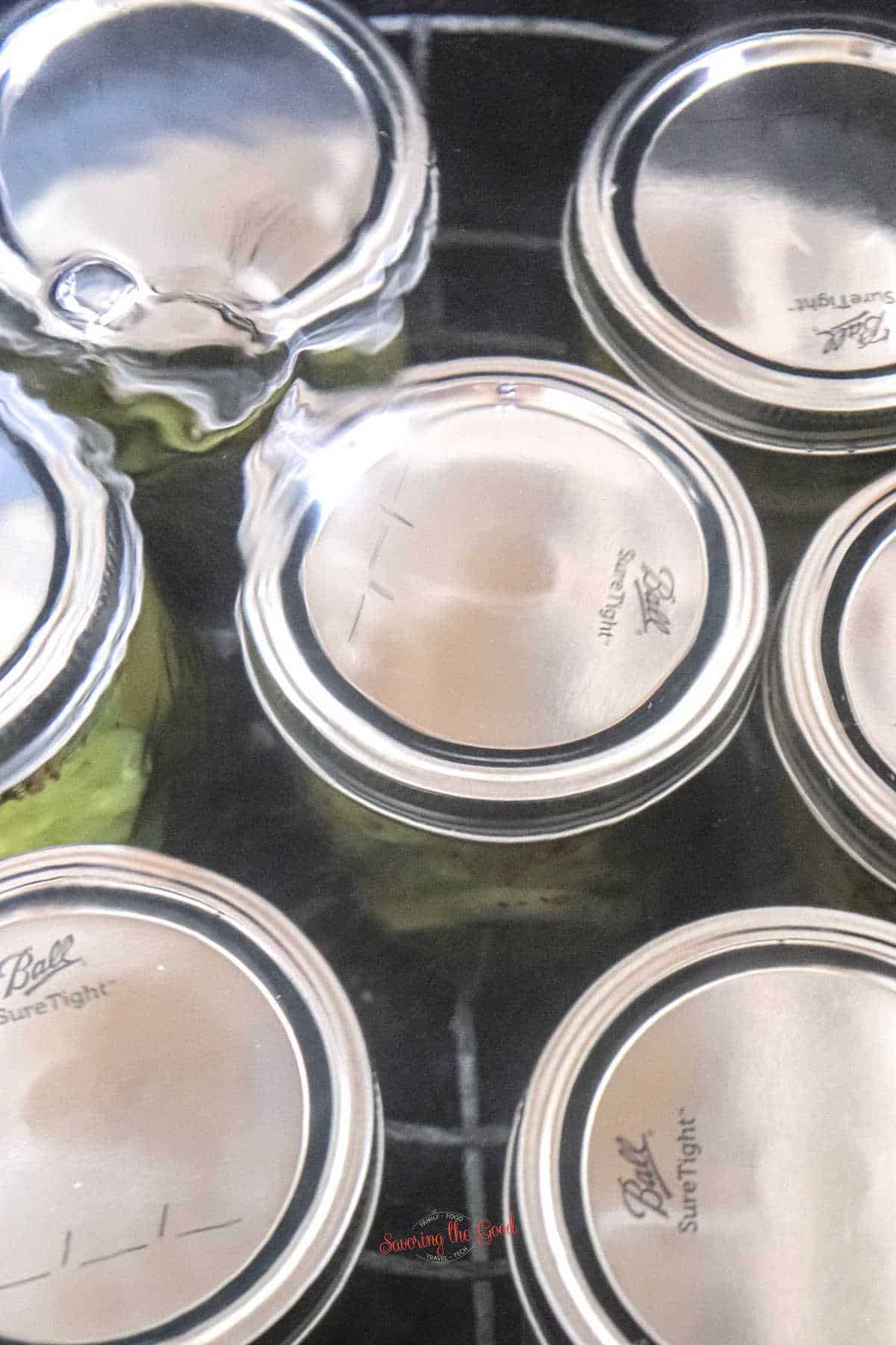 7 jars of pickles being water bath canned under water