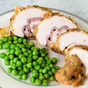 CHICKEN CORDON BLEU sliced on a bone china plate with green peas