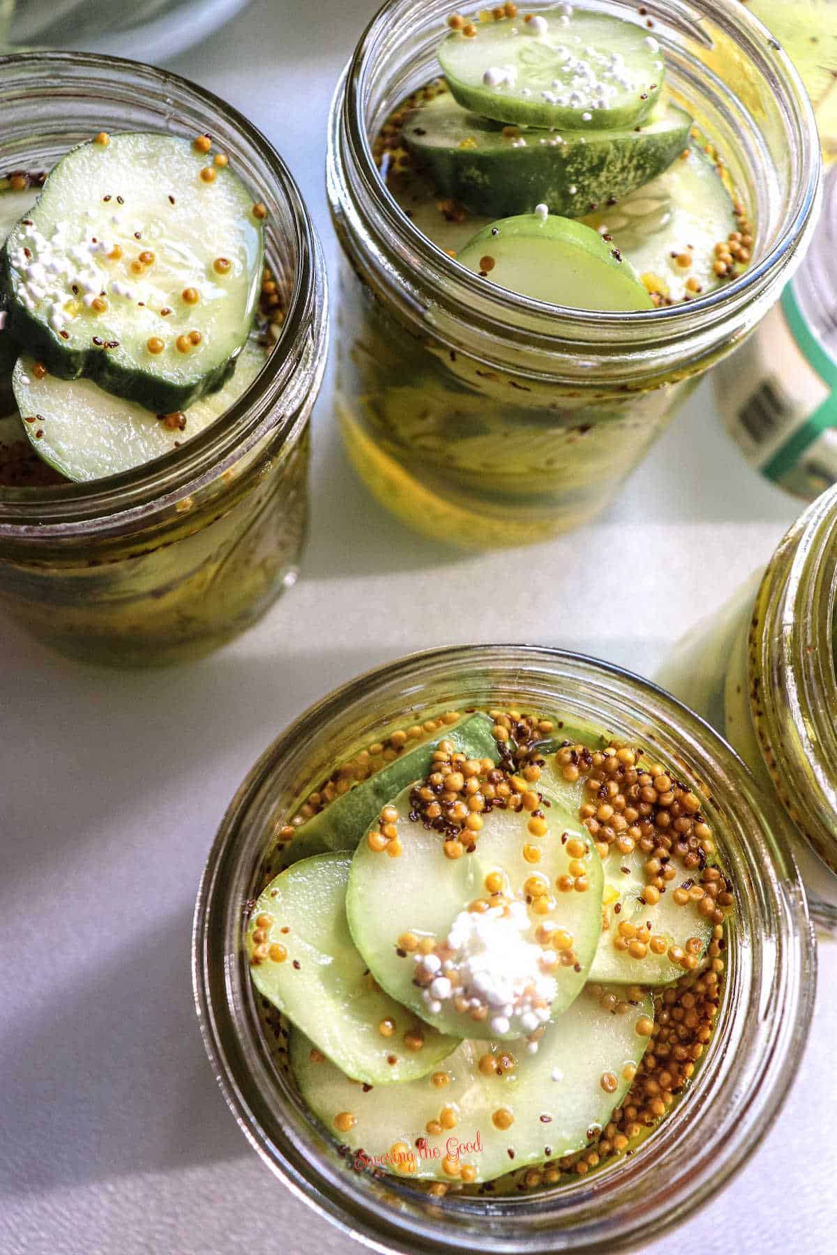 adding spices to the sliced cucumbers in the canning jars, top down image