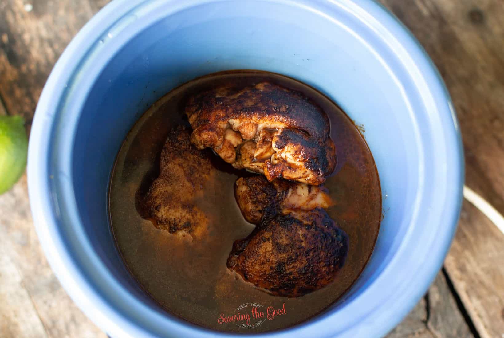 seasoned, seared chicken thighs in a small slow cooker with chicken stock added