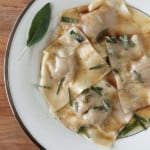 pumpkin ravioli on a plate with brown butter sauce and sage