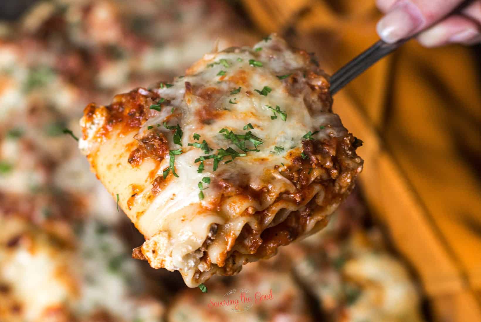 horizontal image of a whole lasagna roll on a serving fork