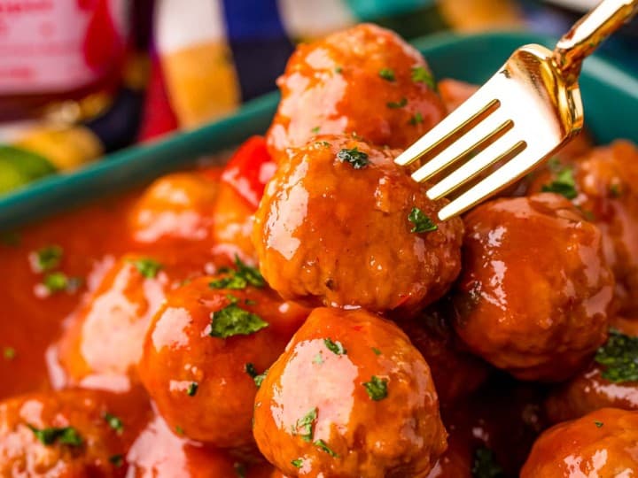 Frozen meatballs in a sauce on a plate with a fork, served as an appetizer.