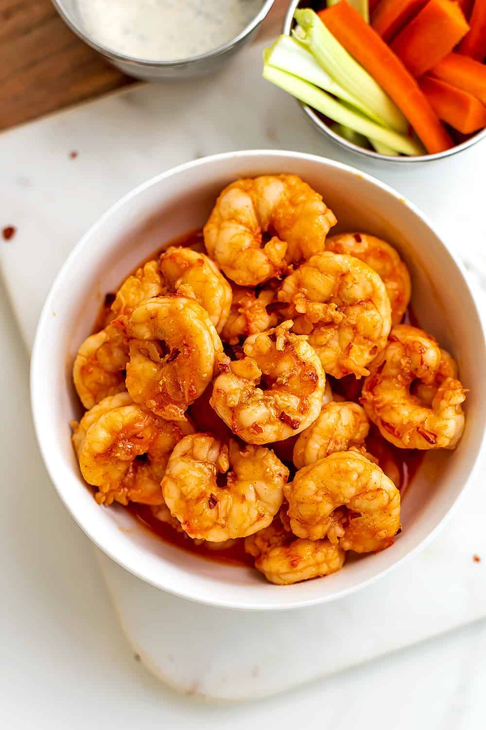 A delectable keto shrimp dish featuring a bowl of fried shrimp and vegetables on a cutting board.