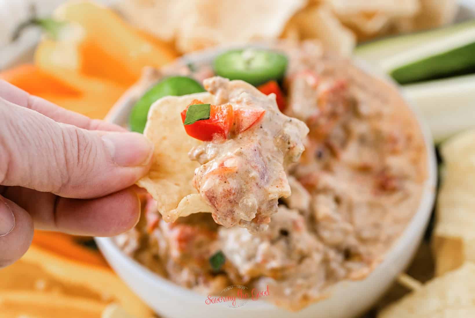 hand holding rotel dip on a scoop chip.
