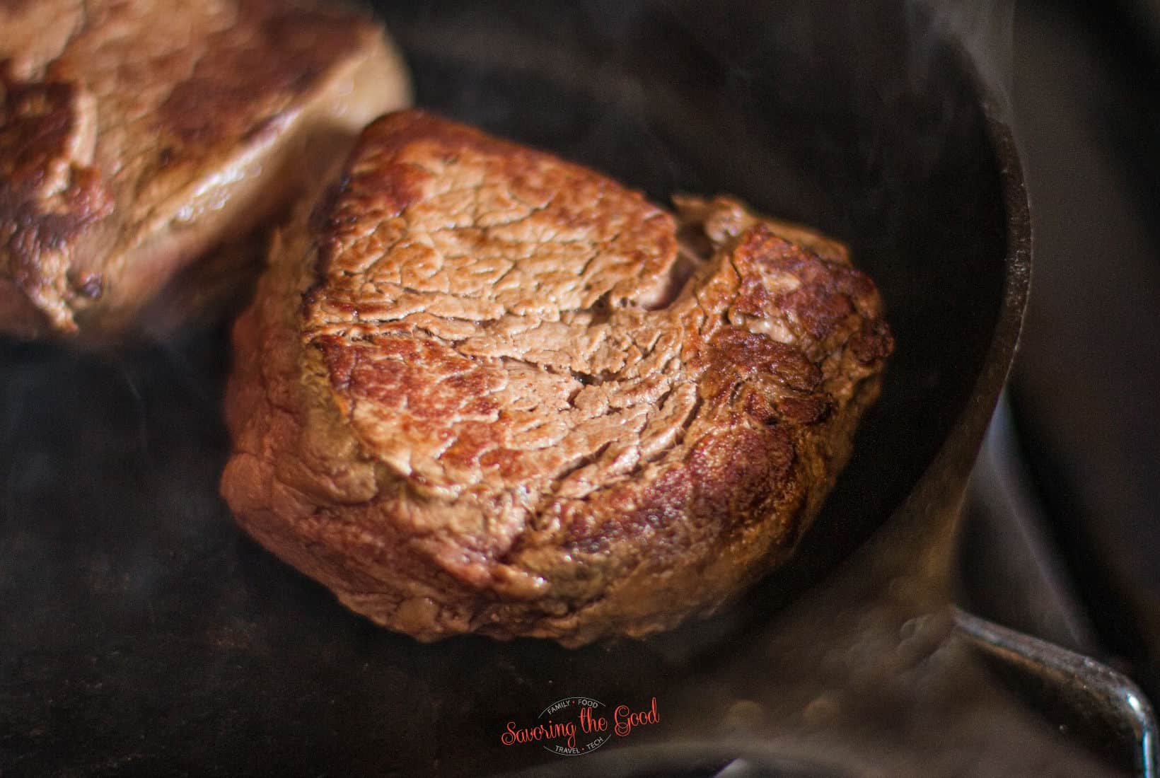seared filet mignon, in a cast iron pan, ready to be cooked further.