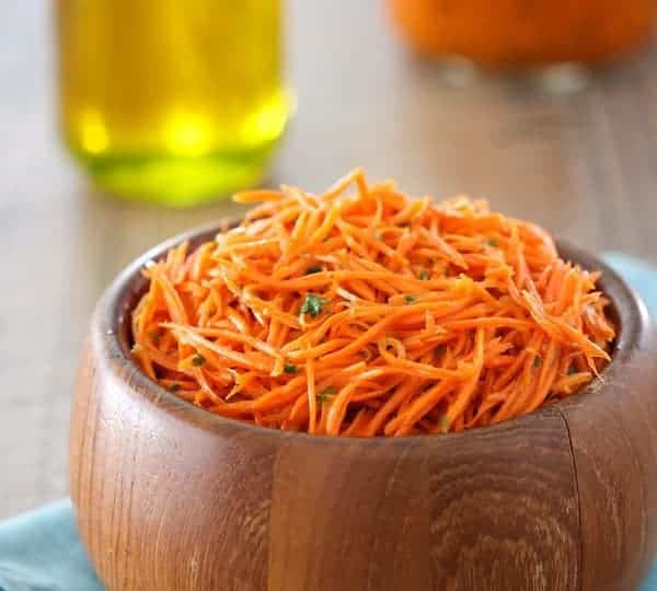 Carrots in a wooden bowl on a wooden table.