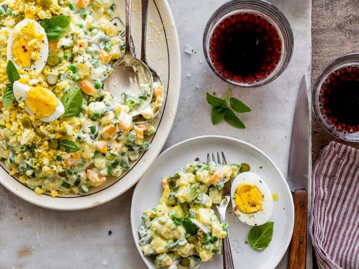 A plate of salad with eggs and herbs on a table.