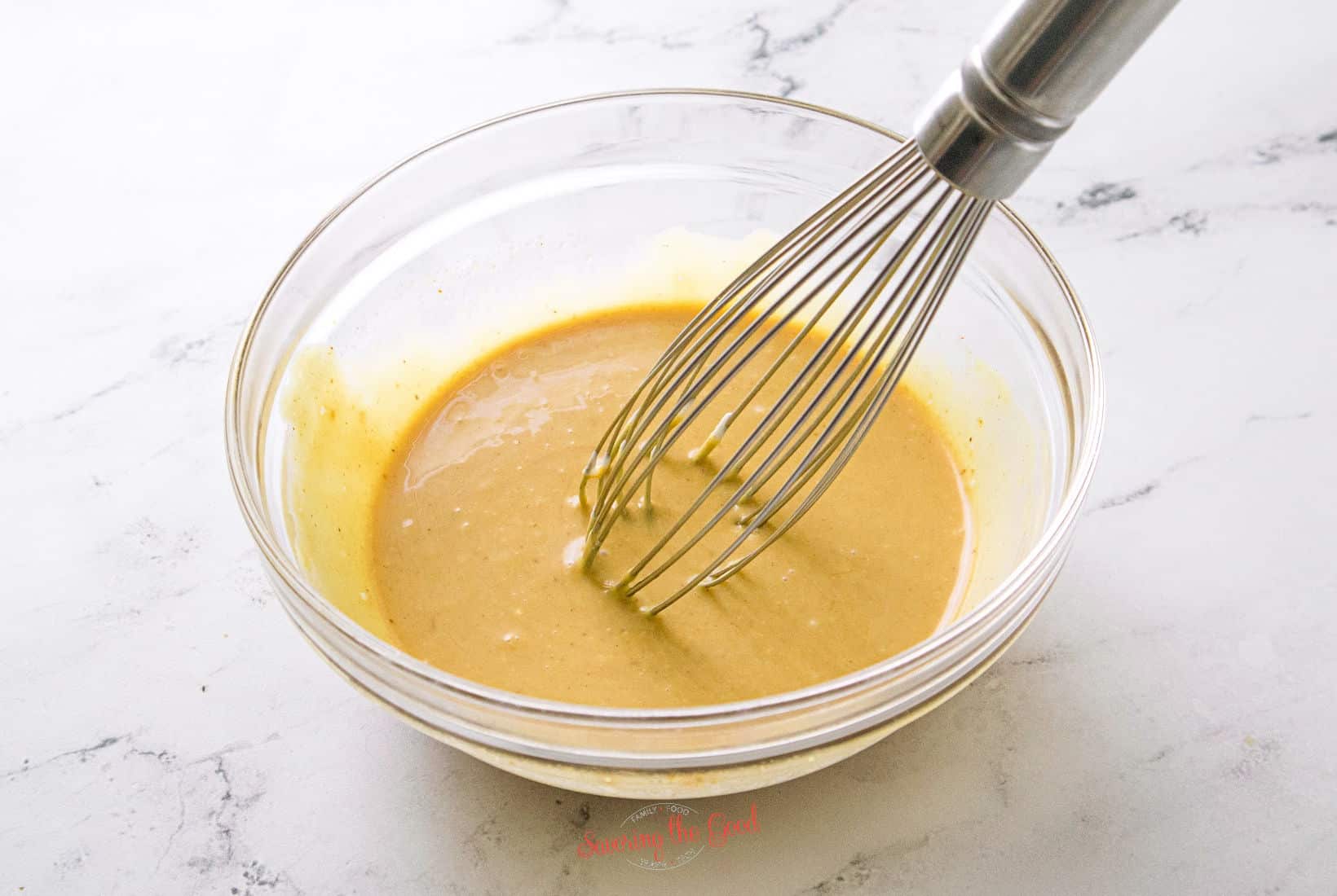 a whisk stirring chick fil a sauce ingredients till blended in a clear glass bowl.