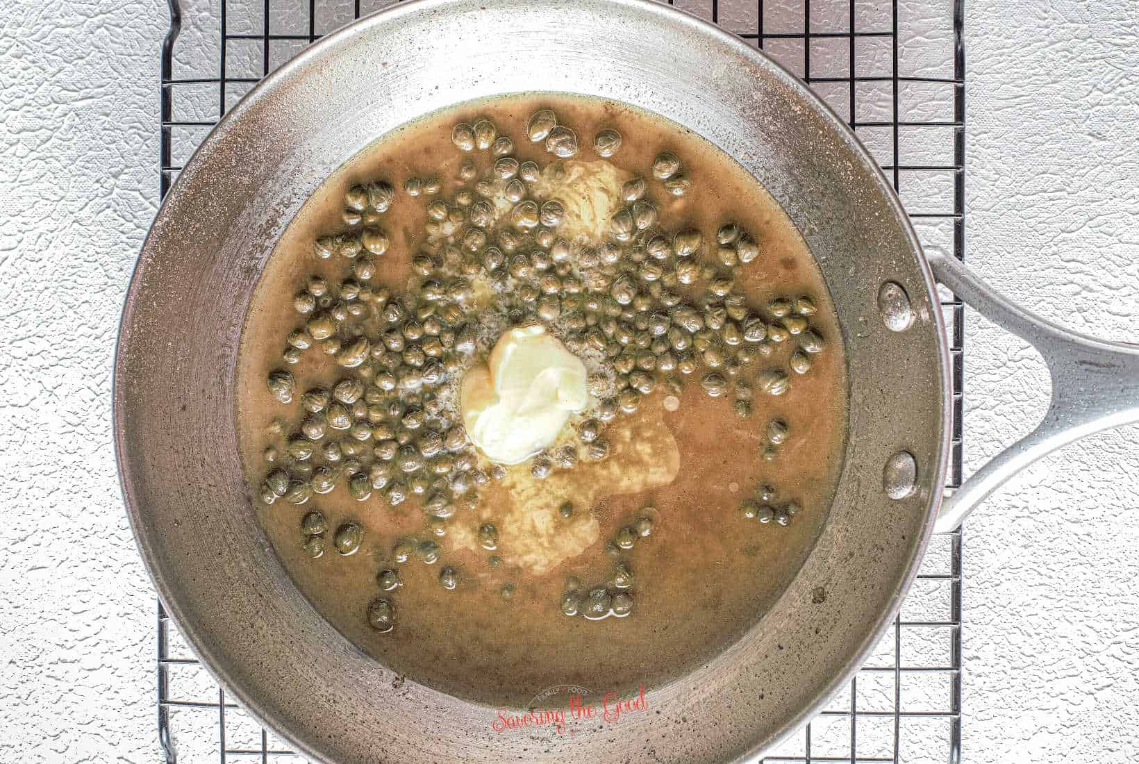 butter added to the sauce, starting to melt and pool in the sauce. Sauce needs to be whisked.