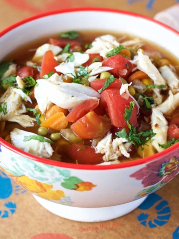 maryland crab soup with lump crab meat, carrot, broth, tomatoes, peppers in a bowl.
