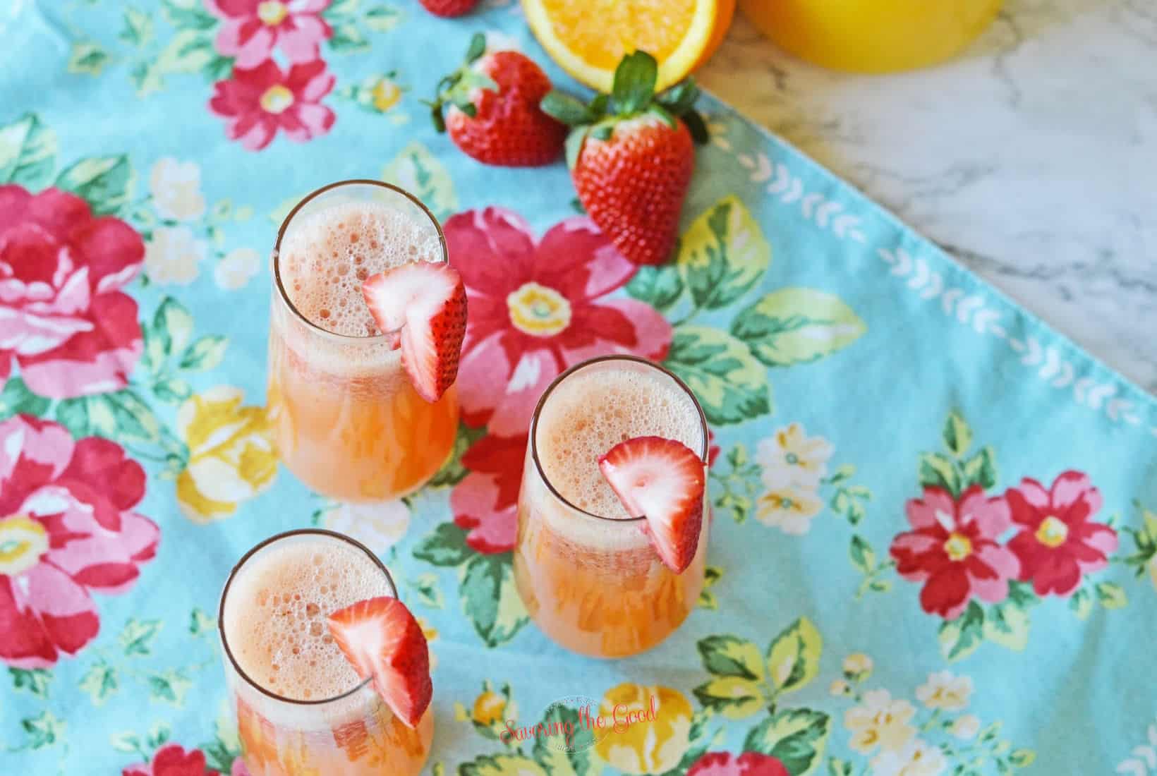 strawberry mimosas in stemless flutes on a bright, floral napkin.