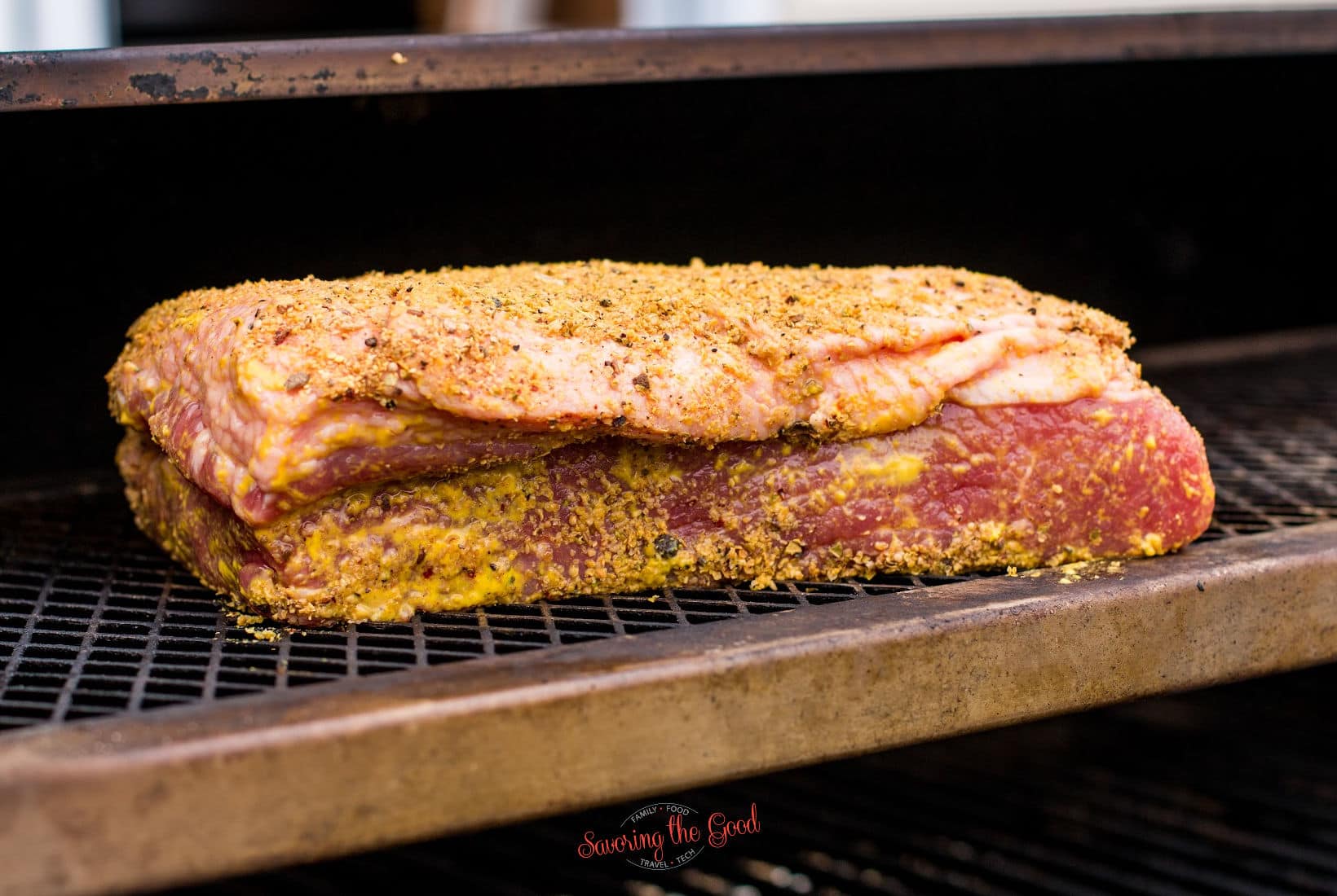 seasoned corned beef, raw, on a rack in a smoker.