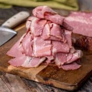 thinly sliced Smoked Corned Beef piled high on a wooden cutting board.