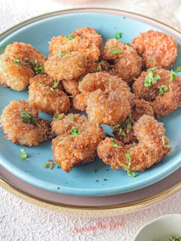 easy crispy popcorn shrimp on a blue plate and parsley garnish, square image.