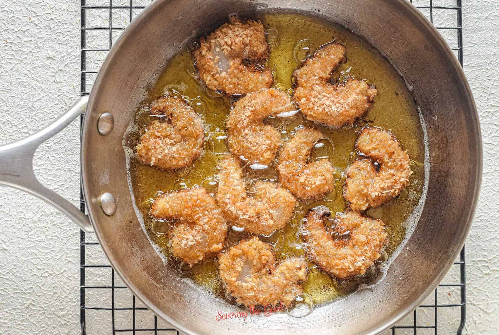 popcorn shrimp frying in a pan with 1:4 inch of fry oil.