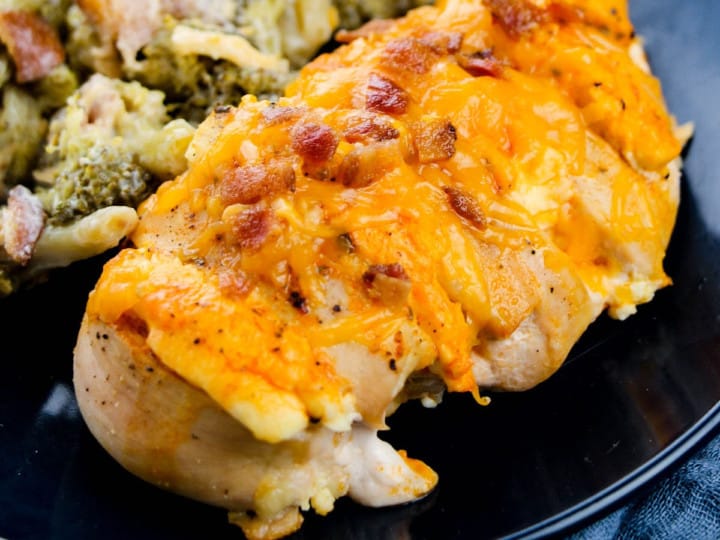 Hasselback Chicken with bacon and cheese on a dark blue plate.