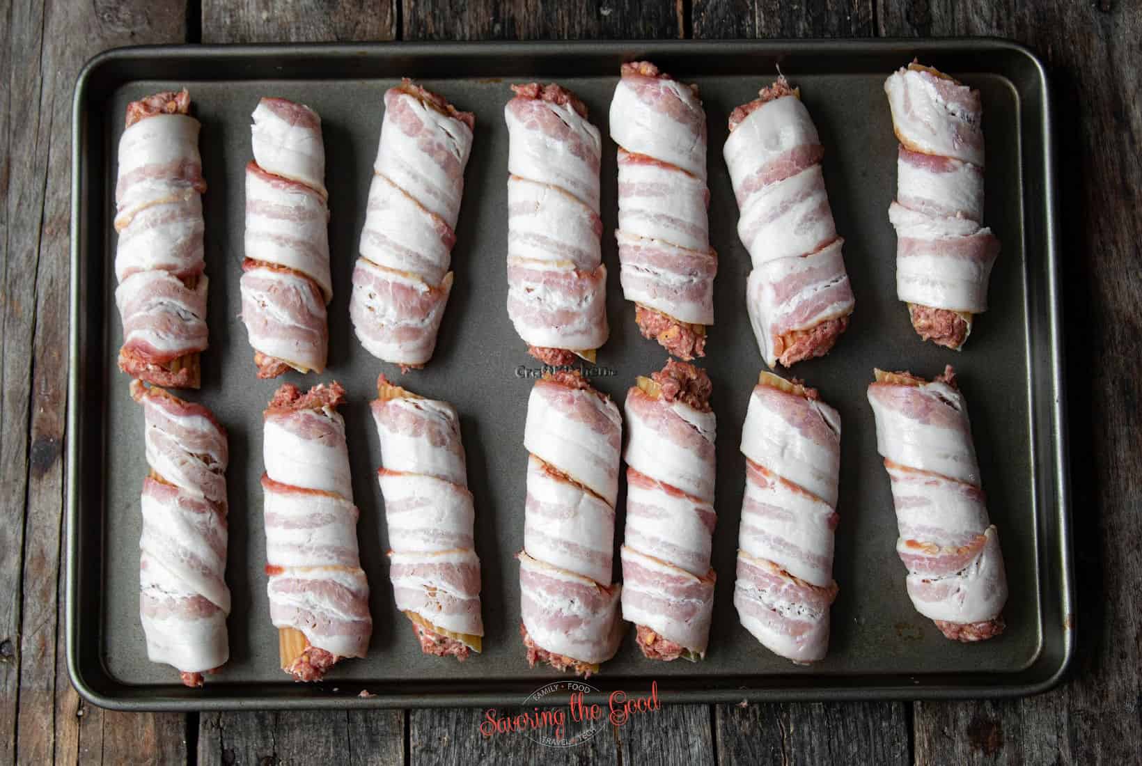 14 bacon wrapped, stuffed Smoked Shotgun Shells on a baking sheet.