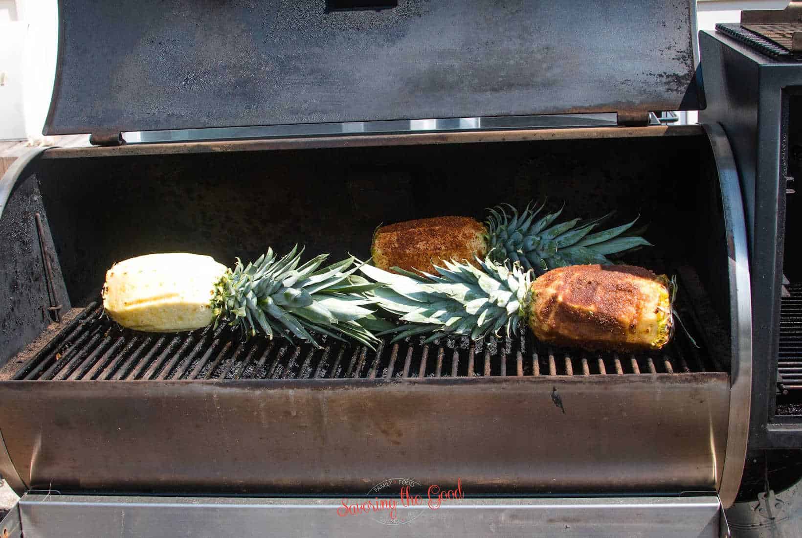 3 peeled pineapples on a pellet smoker, ready to be cooked.