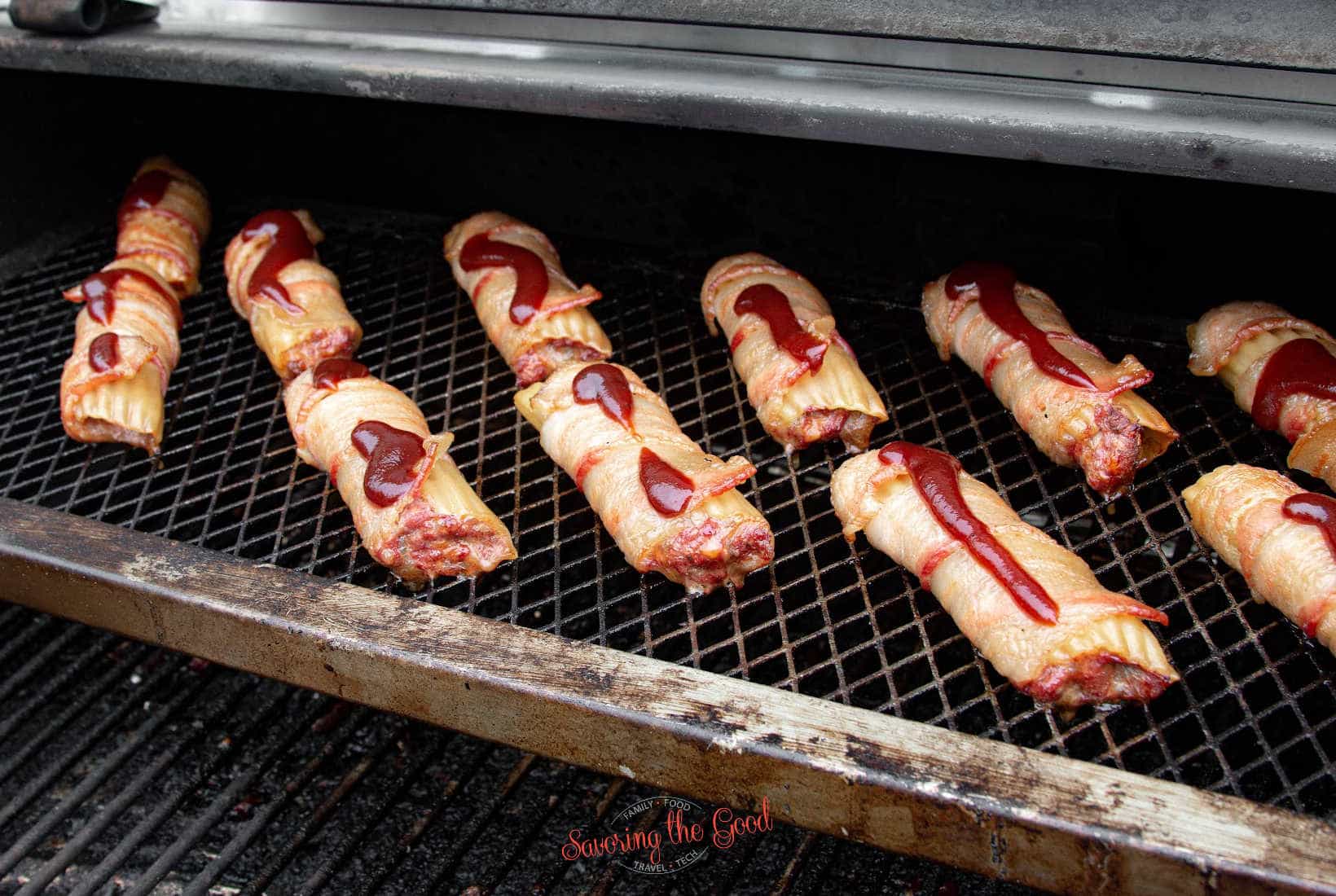 a squirt of bbq sauce on each of the Smoked Shotgun Shells on a smoker grate.