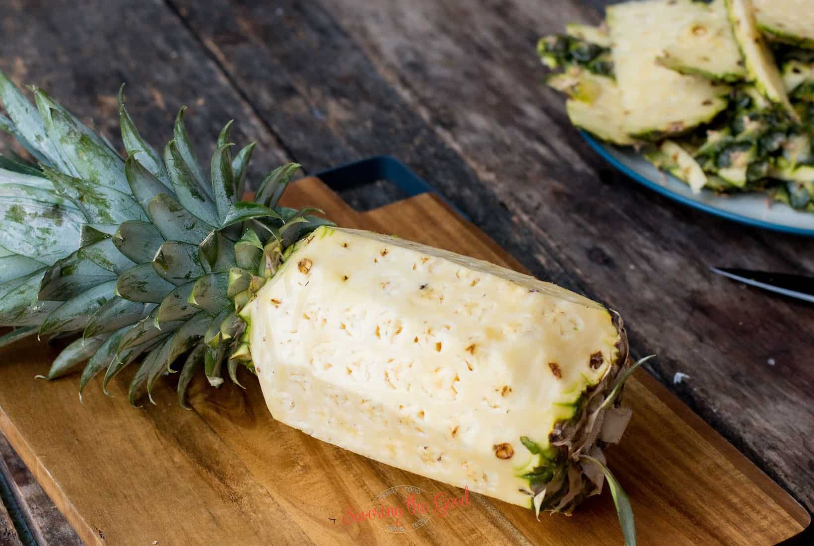 horizontal image of a peeled pineapple, pineapple top in place.