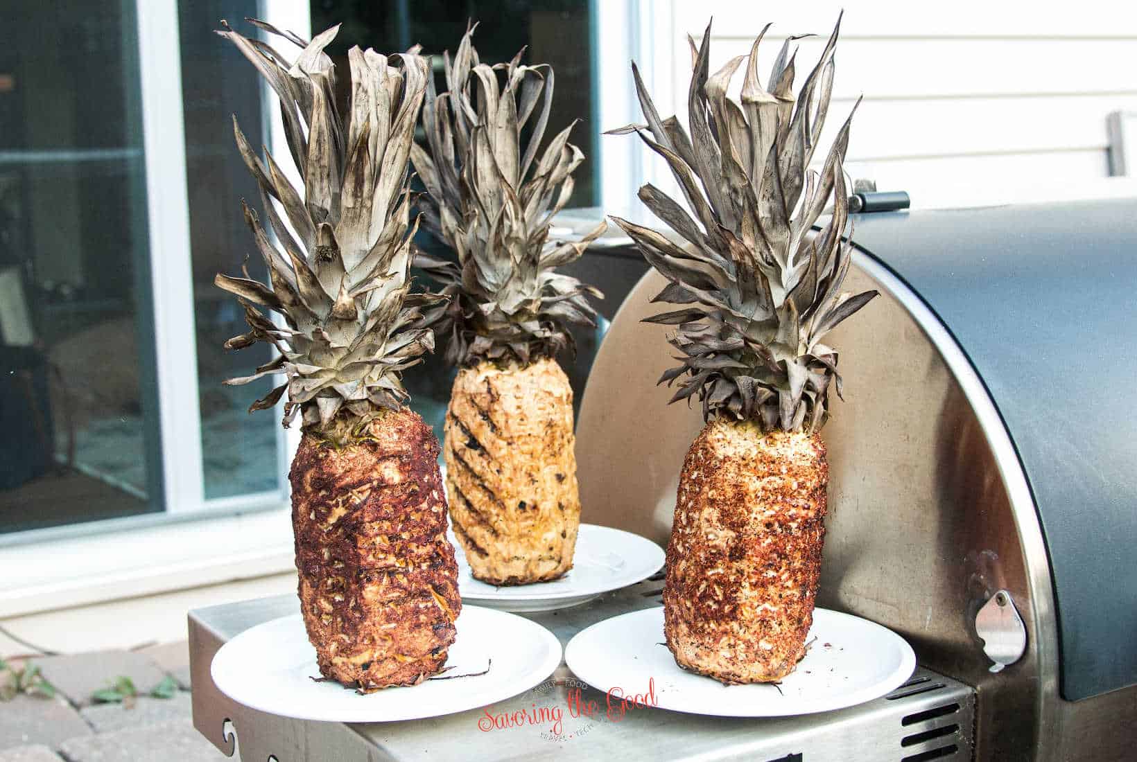 plain Smoked Pineapple, brown sugar and cinnamon Smoked Pineapple, and tajin Smoked Pineapple on white plates next to a smoker grill.