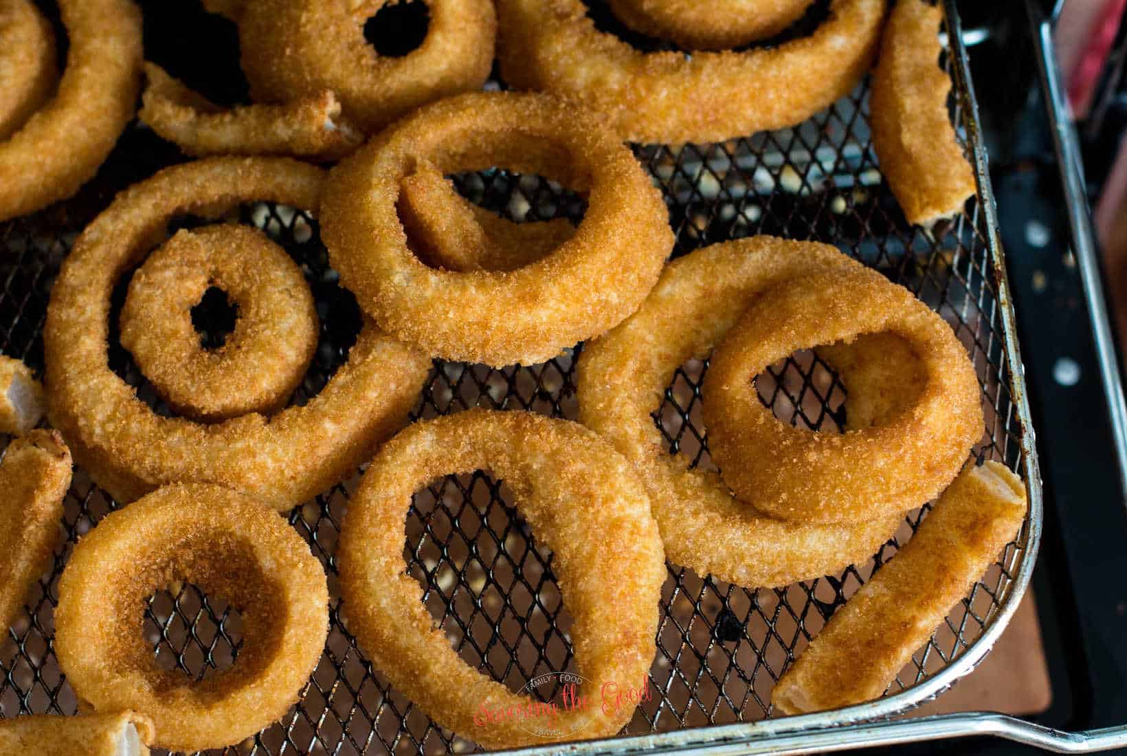 horizontal image of air fried onion rings on a air frier basket.