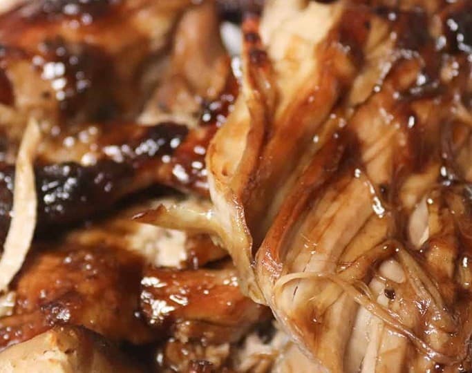 Close-up of shredded pulled pork with dark barbecue sauce, embodying the tender flavors of pork loin perfected in crockpot recipes.