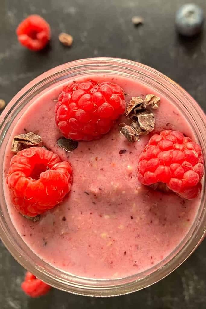 Vegan Berry Smoothie with coco nibs and fresh raspberry garnish.