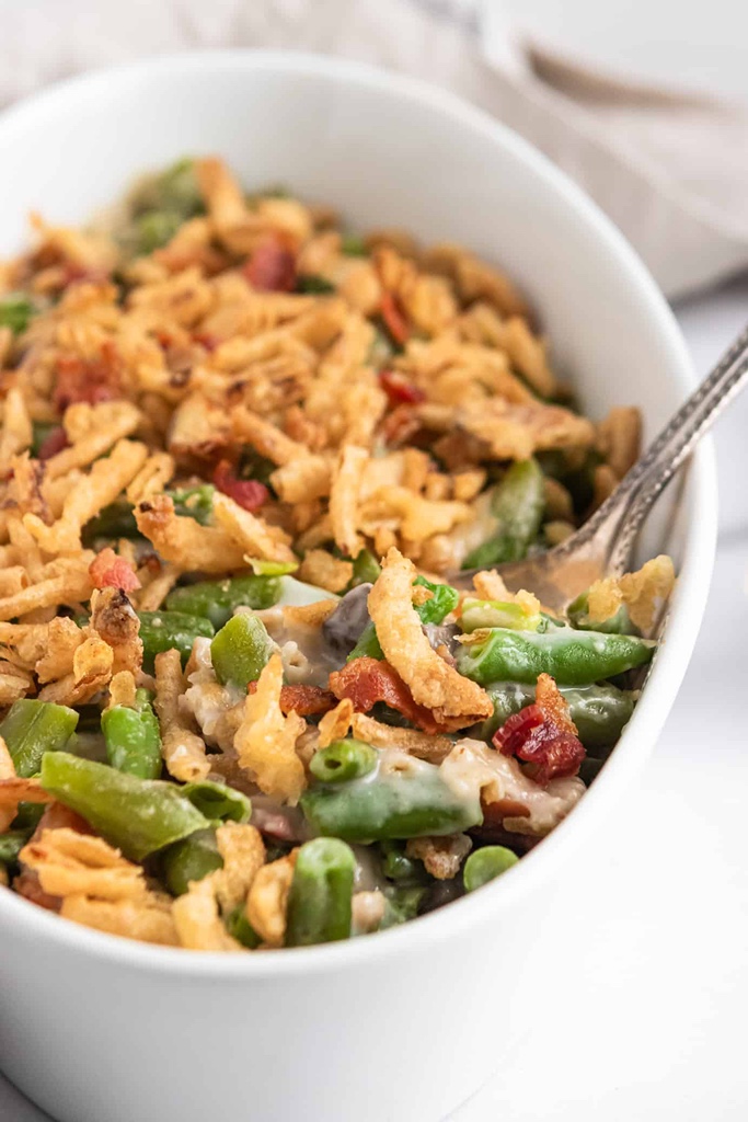 green bean casserole with bacon in a white serving dish.
