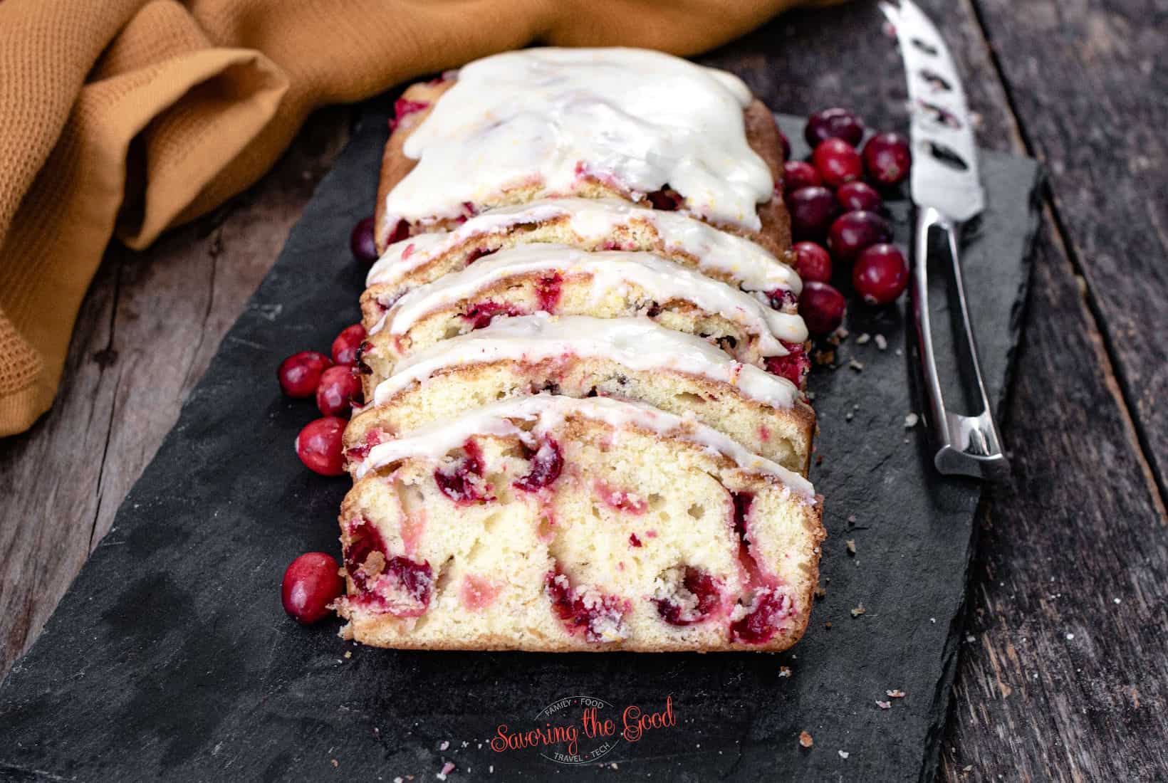 icing coated cranberry bread, sliced on a slate serving dish.