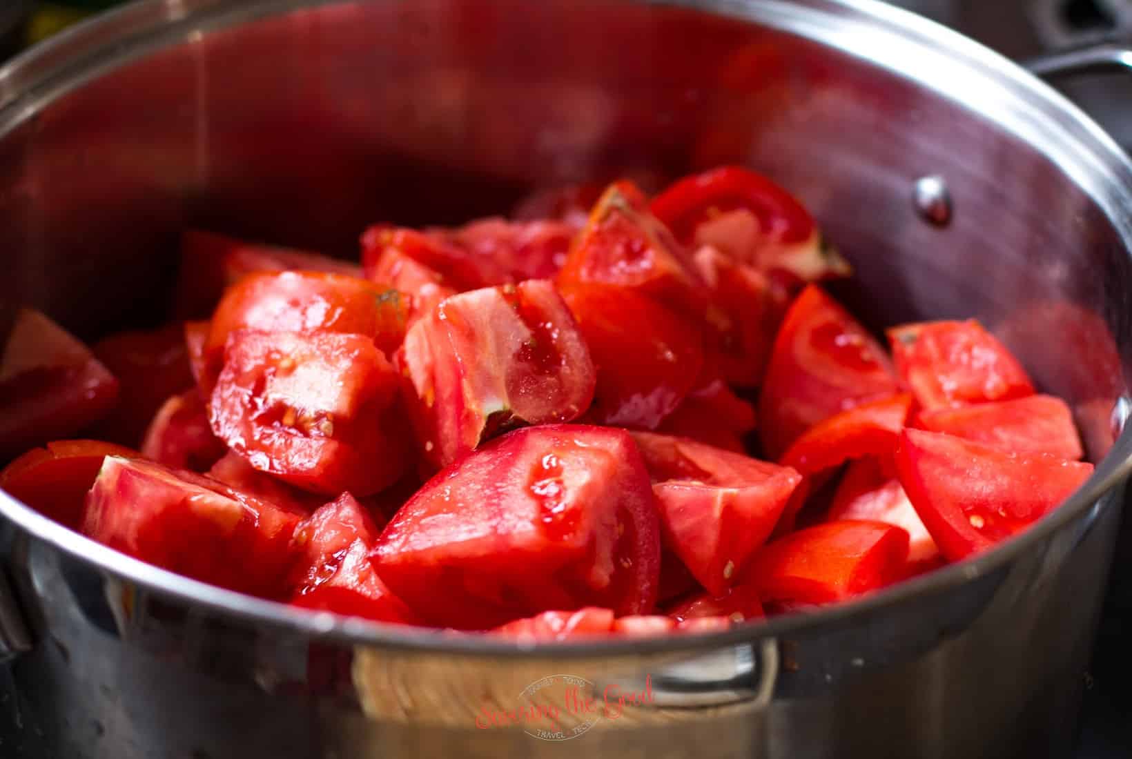 quartered tomatoes piled up in a pan to cook.