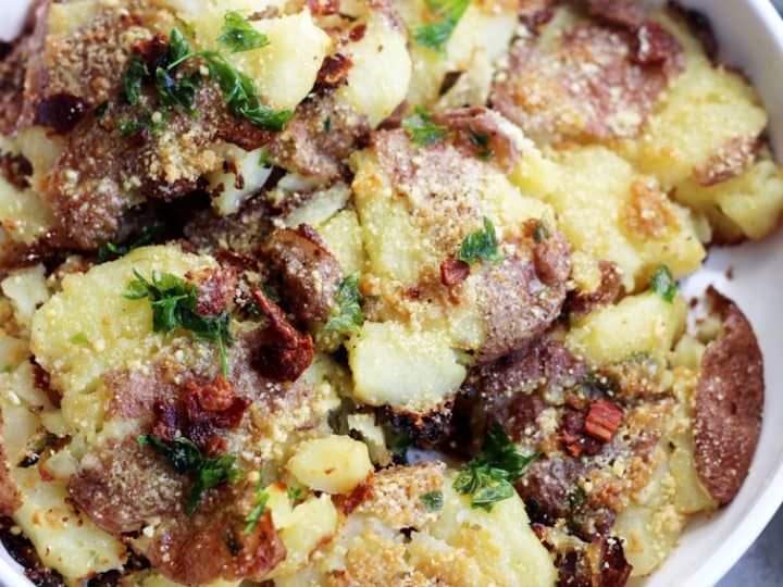 A delightful dish featuring smashed roasted baby potatoes, crowned with crispy bacon bits, grated Parmesan, and fresh parsley. Perfect for those searching for irresistible baby potatoes recipes.