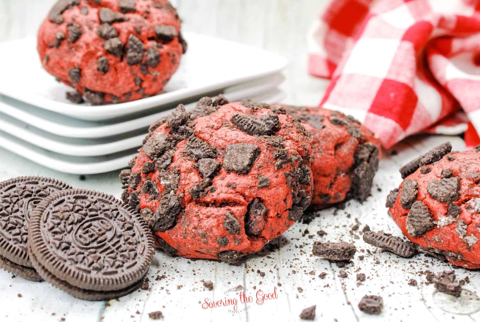 2 Oreo Red Velvet Cookies with whole oreos to the side and a red checked cloth to the back.