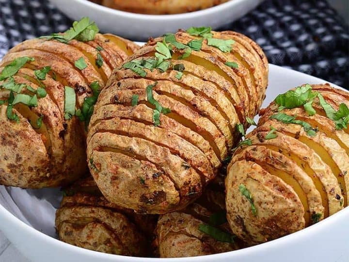 A white bowl with fried potatoes and chicken wings.