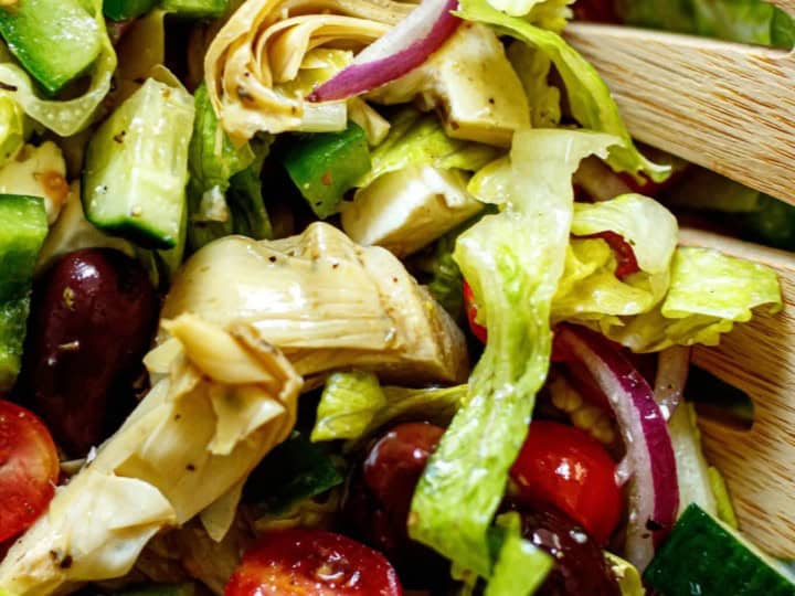 A salad with olives, tomatoes, and cucumbers, perfect as a side for lamb chops.